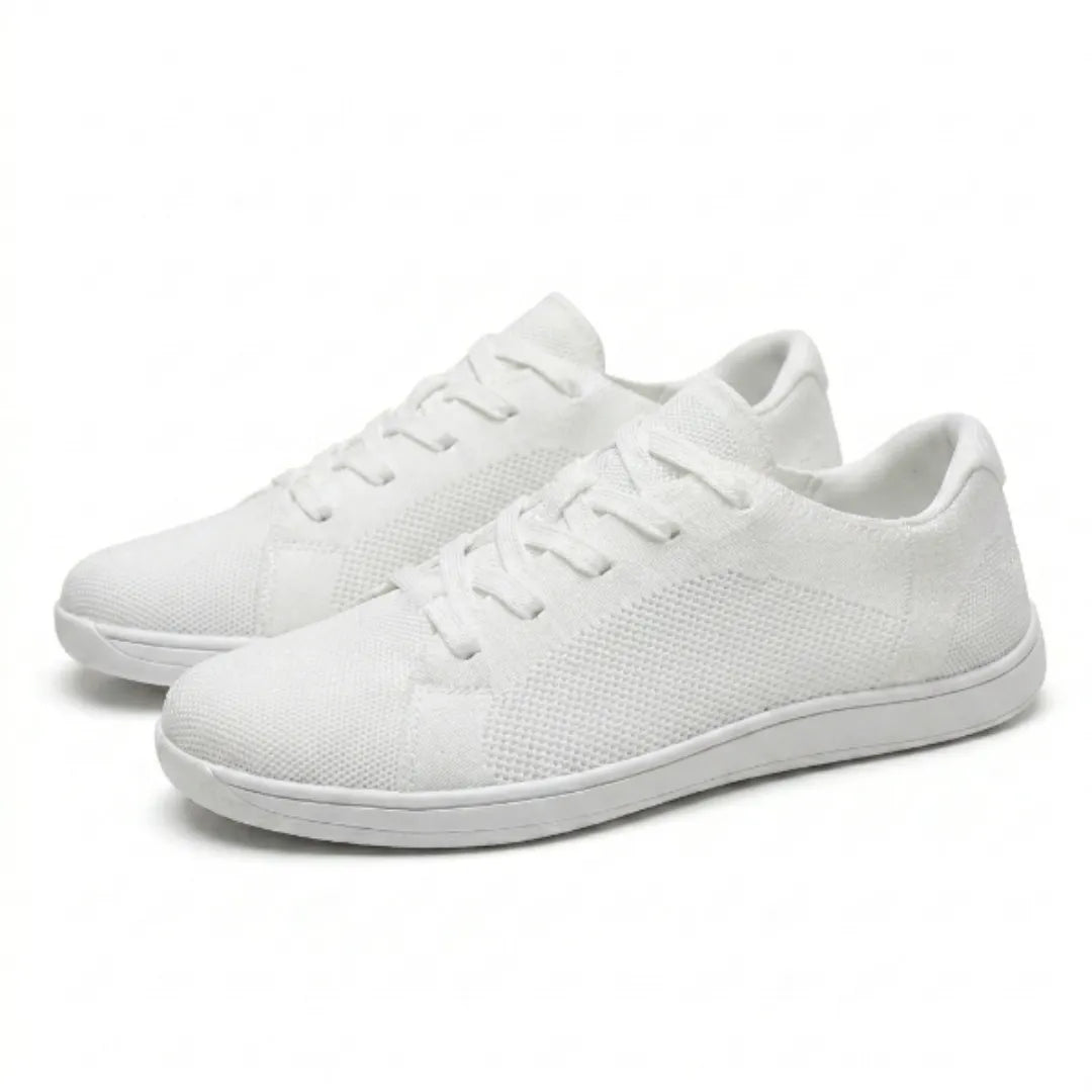 Paar witte gebreide barefoot-sneakers met veters en dunne witte zool, schuin van opzij gefotografeerd op een lichte achtergrond. 43