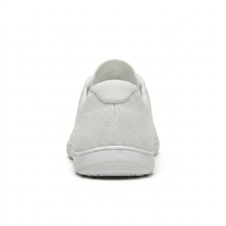 Achterkant van een witte gebreide sneaker met hielstuk van mesh en dunne witte zool op een witte achtergrond. 45