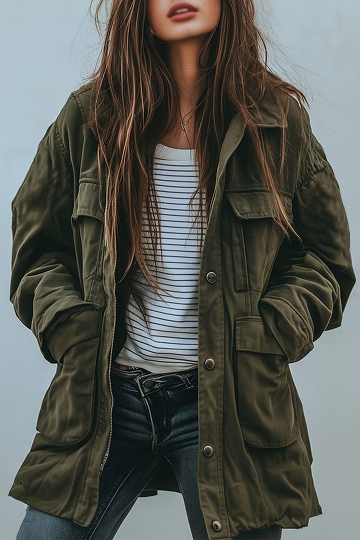 Model draagt de olijfgroene utility-jack open over een gestreept shirt en donkere jeans, met de handen in de zakken. 1