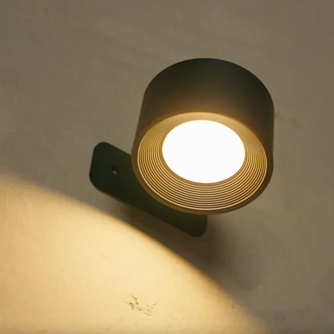 Zwarte wandlamp van schuin onderaf, met een lichtcirkel op de muur eronder 3