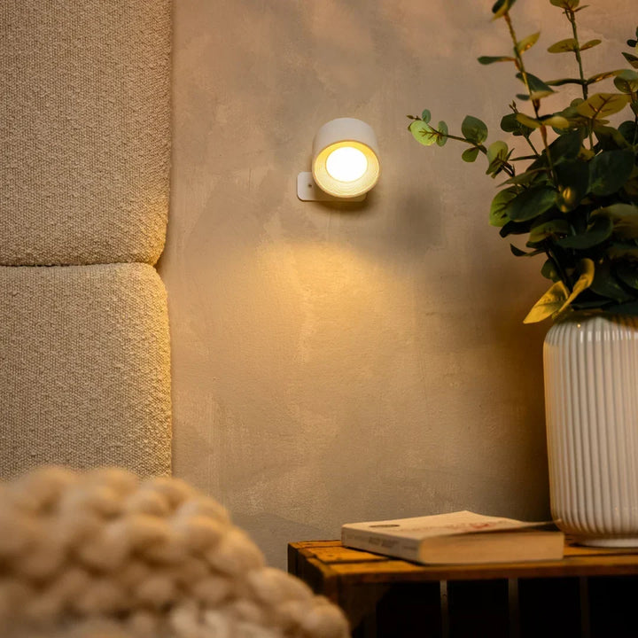 Witte wandlamp brandt boven een houten krat met boek, naast een gebouwd stoffen hoofdbord 7