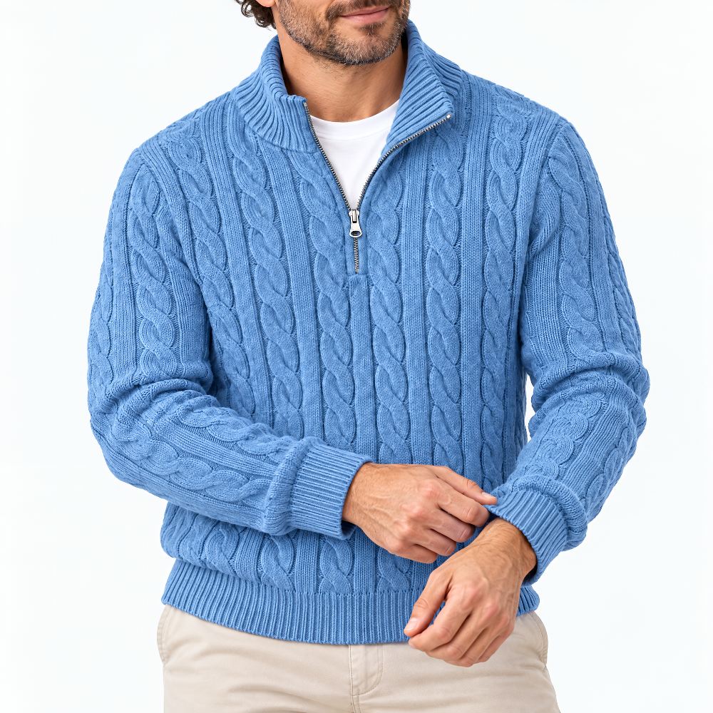 Man draagt blauwe kabeltrui met halve rits over wit shirt, bijgesneden voorkant met ribboorden en beige broek. 1
