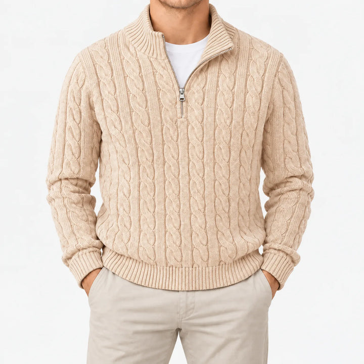 Beige kabeltrui met halve rits en ribboorden gedragen over wit shirt, studiofoto van de voorkant met lichte broek. 14