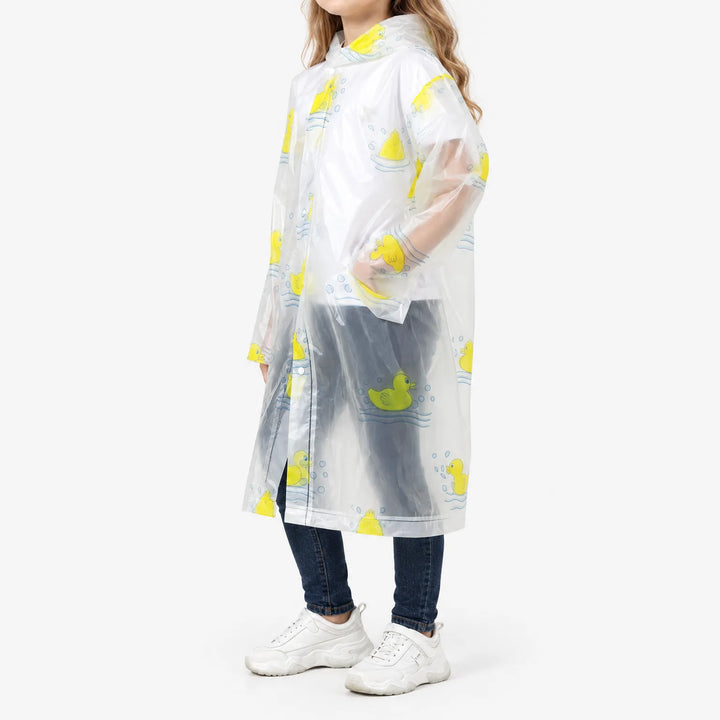 Zijaanzicht van een meisje in de doorzichtige regenjas met gele badeendjes, met een hand in de zijzak, over spijkerbroek en witte sneakers. 5