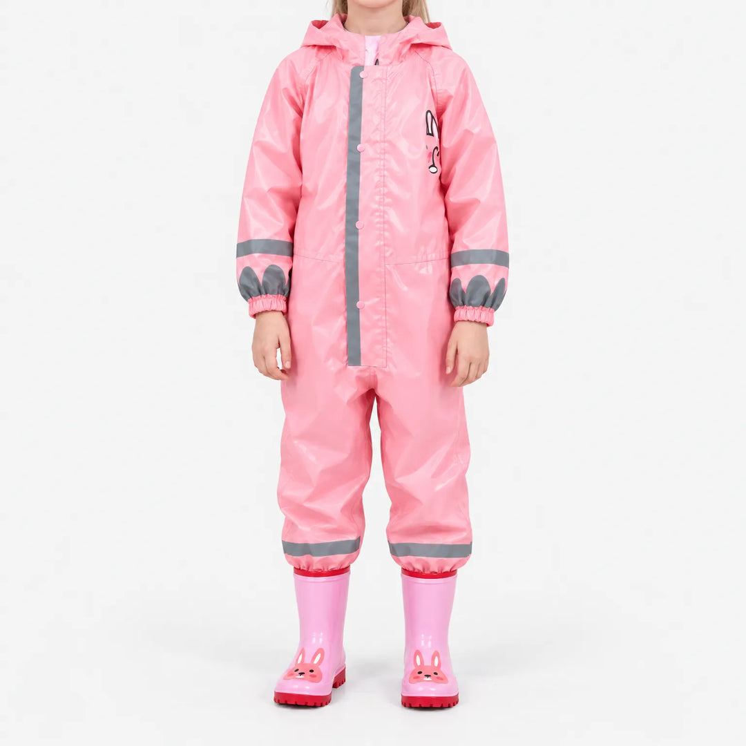 Voorkant van het roze regenpak met glanzende stof en reflecterende strepen, gedragen met roze laarzen met konijnengezichtje tegen een witte achtergrond. 9
