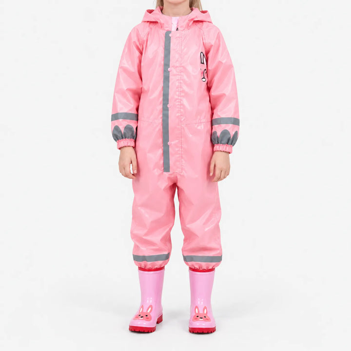Voorkant van het roze regenpak met glanzende stof en reflecterende strepen, gedragen met roze laarzen met konijnengezichtje tegen een witte achtergrond. 9