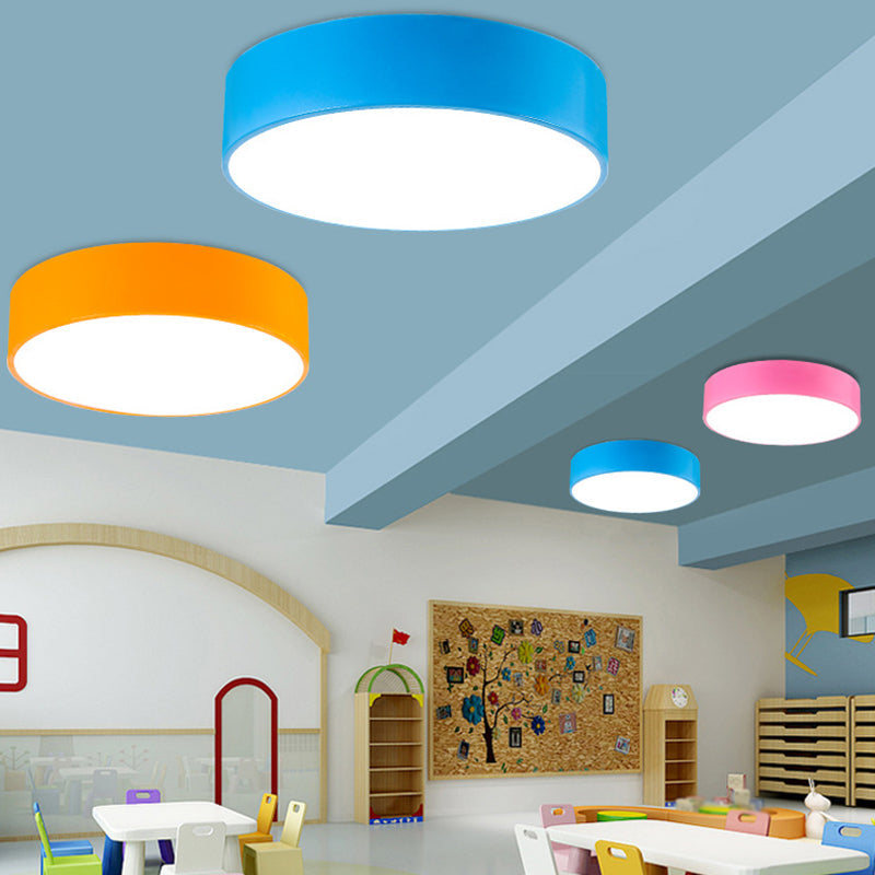 Blauwe, oranje en roze ronde plafondlampen aan een blauw plafond in een speelse kinderruimte met tafeltjes 4