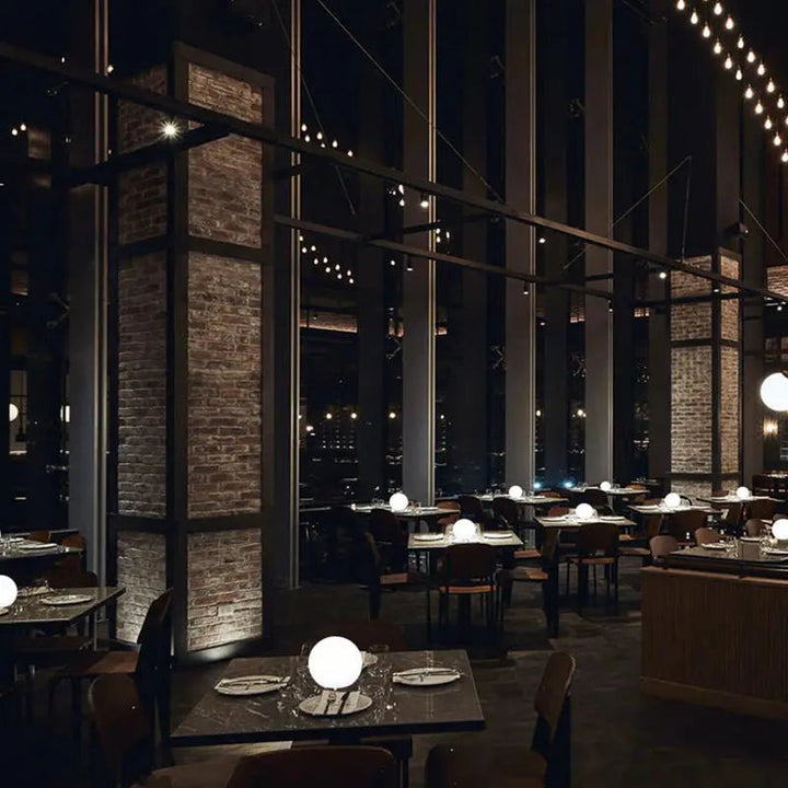 Sfeervol restaurant met bakstenen pilaren, waar op elke gedekte tafel een oplichtende ledbol staat. 8