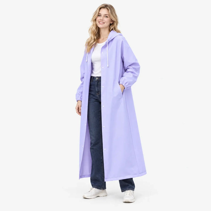 Lachend model in lavendelkleurige lange regenjas met capuchon, de hand in de zak, gecombineerd met wit shirt en spijkerbroek. 4