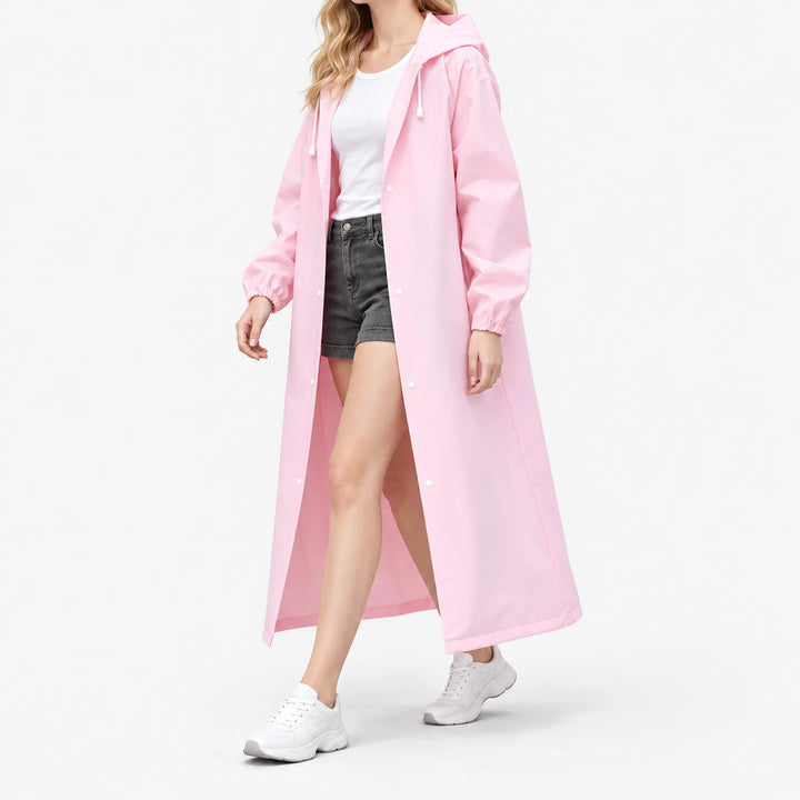 Model loopt in roze lange regenjas met capuchon en drukknopen, open gedragen over wit shirt en korte spijkerbroek, op witte achtergrond. 5