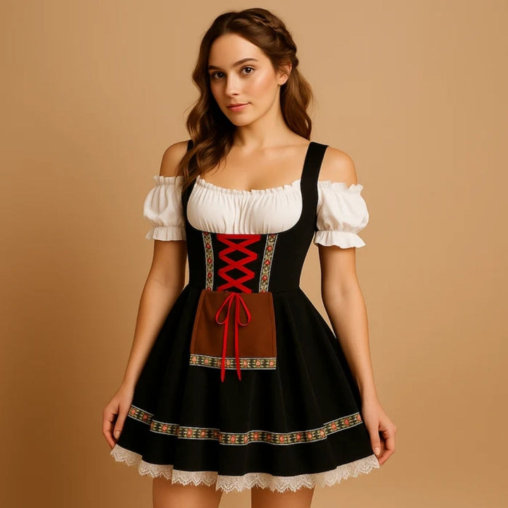 Model draagt een zwarte dirndl met rode kruisveters, bruin schortje, bloemenband langs de zoom en een witte kanten rand. 7