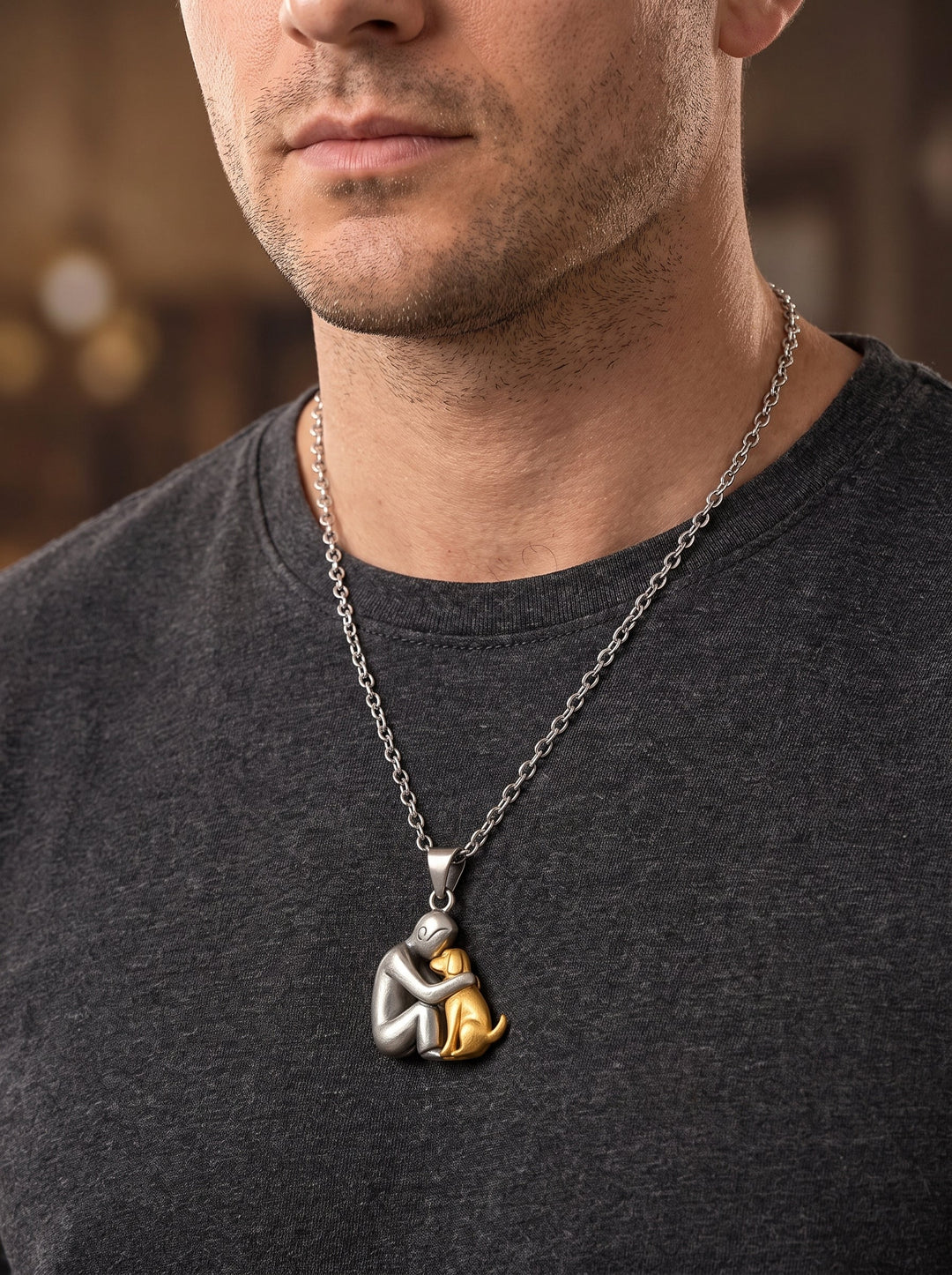 Man in een donkergrijs T-shirt draagt de ketting met een mat zilverkleurige figuur en een goudkleurige hond als hanger. 11