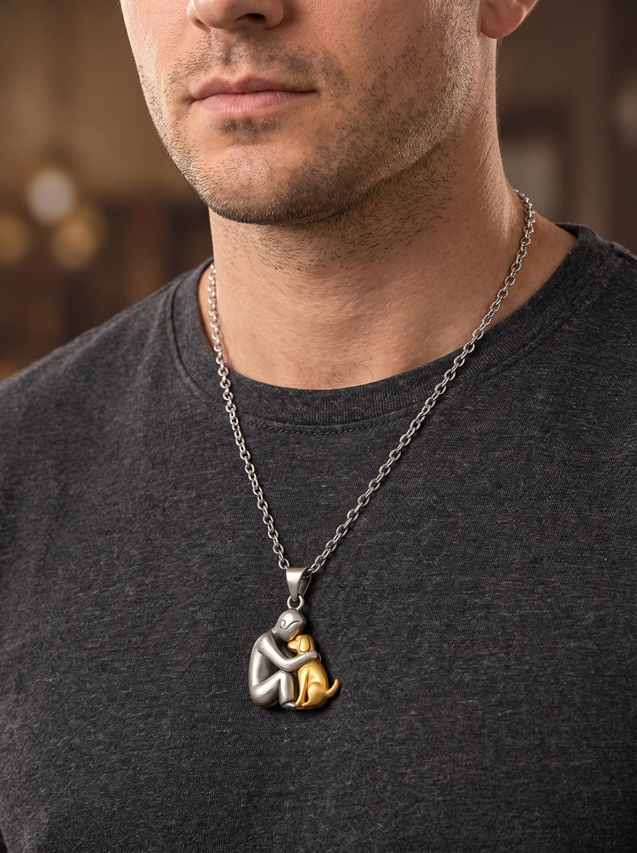 Man in een donkergrijs T-shirt draagt de ketting met een mat zilverkleurige figuur en een goudkleurige hond als hanger. 11