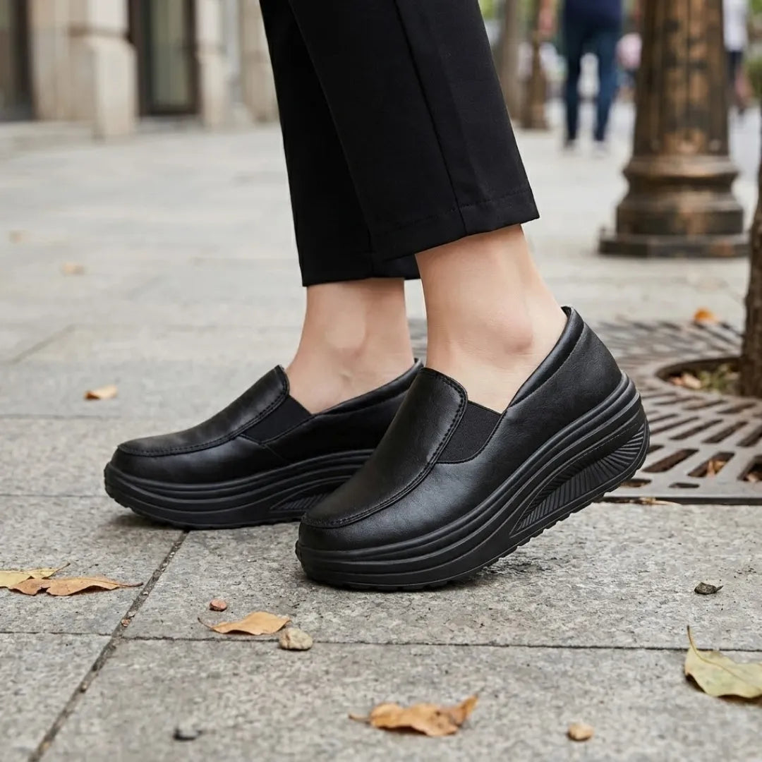 Model draagt zwarte instapschoenen met brede zool op een stoep met herfstbladeren 2