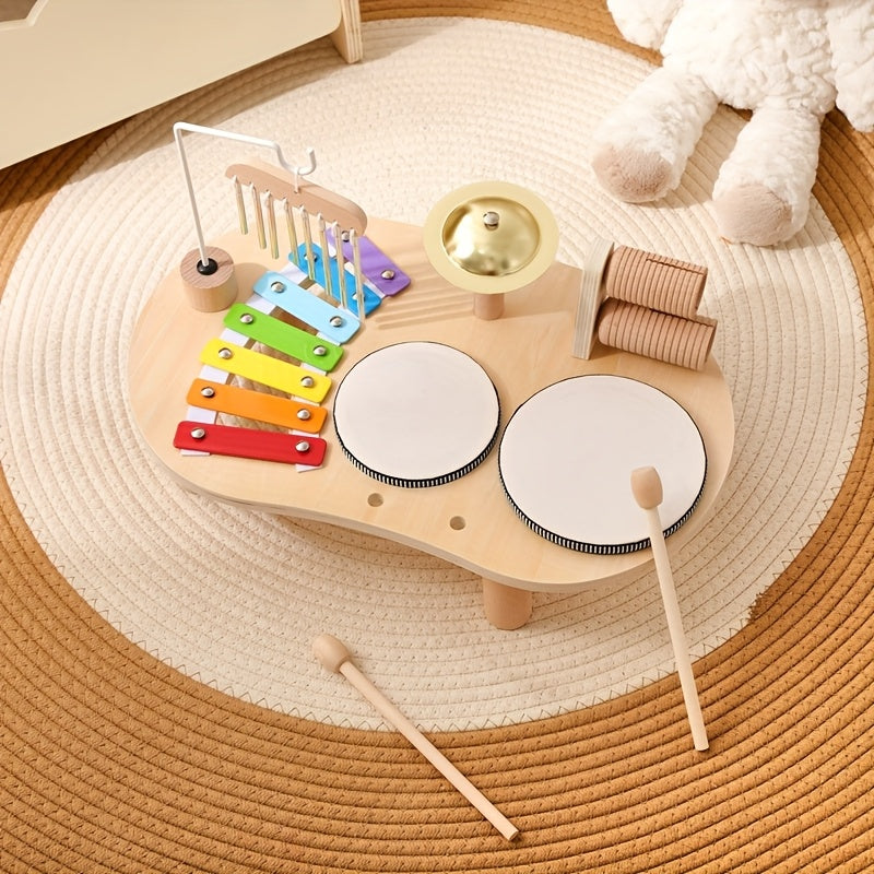 Bovenaanzicht van de muziektafel op een rond gevlochten kleed, met twee houten stokjes los ervoor en een knuffel in de hoek. 8