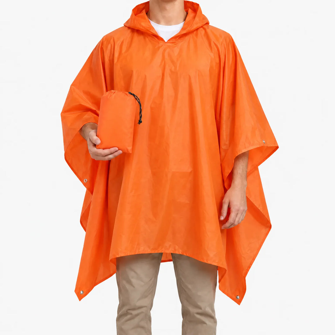 Oranje poncho met capuchon gedragen door een man, die het bijbehorende opbergzakje met trekkoord in zijn hand houdt. 2