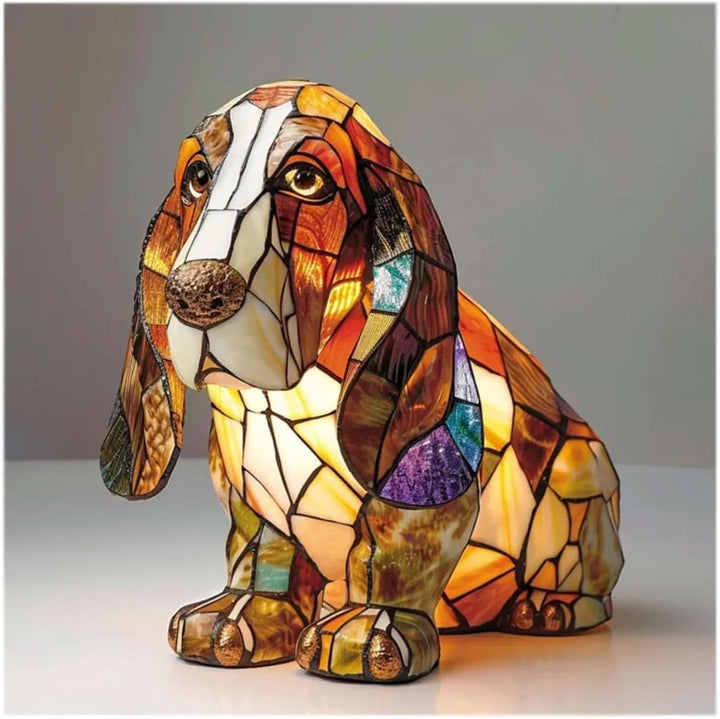 Zittende basset hound als gebrandschilderd lampje met lange hangende oren, bruine en witte glasdelen en een warme gloed van binnenuit. 2