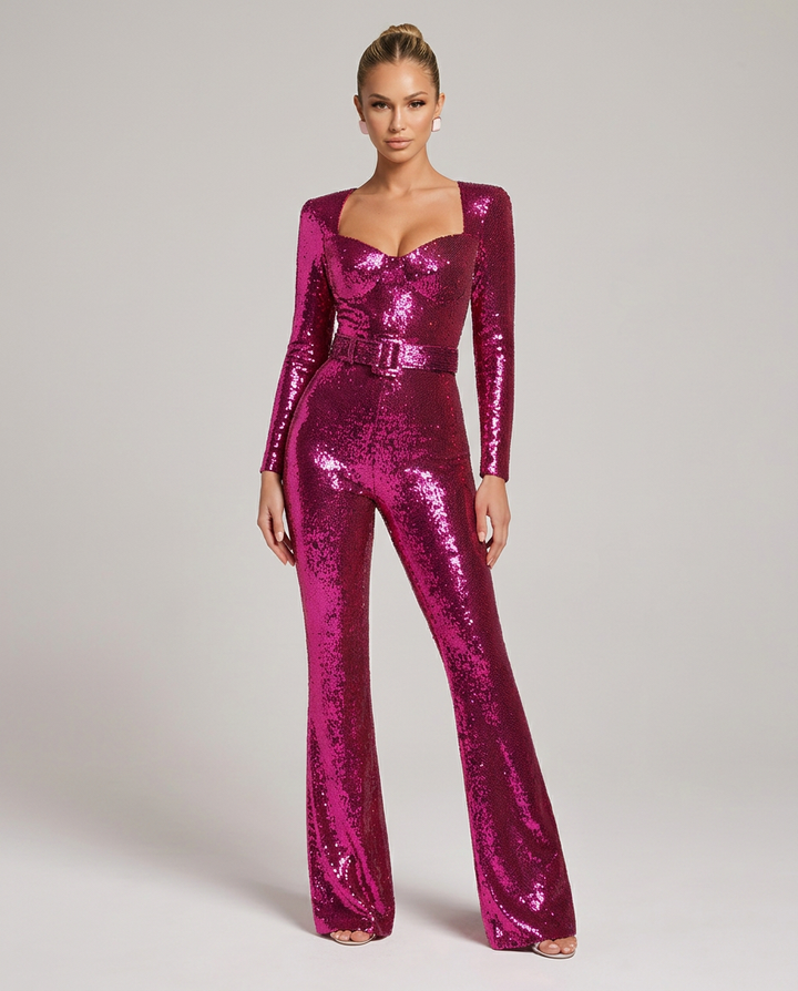 Voorkant van de fuchsiaroze paillettenjumpsuit met uitlopende pijpen, gedragen door een model dat recht naar de camera staat. 1