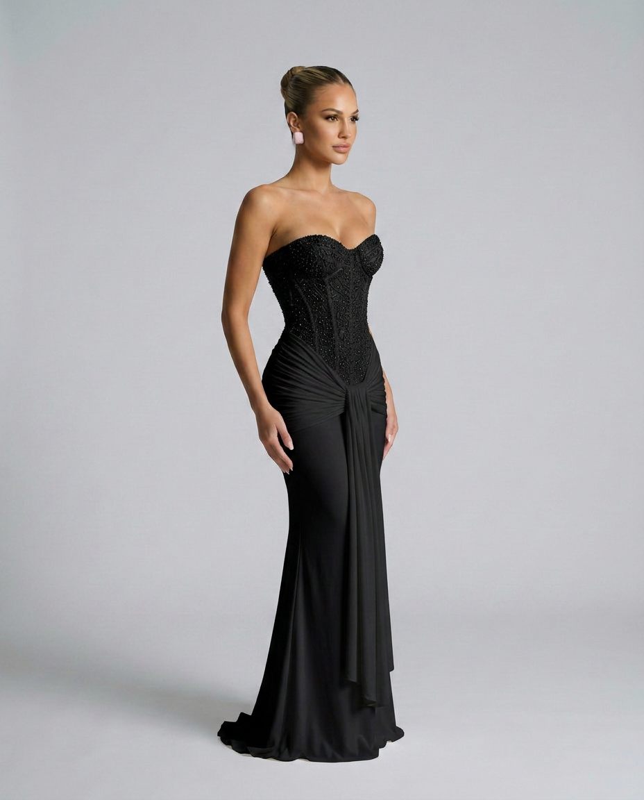 Zwarte strapless jurk met kralenlijfje en gedrapeerde strook, in driekwartprofiel gedragen door model 2