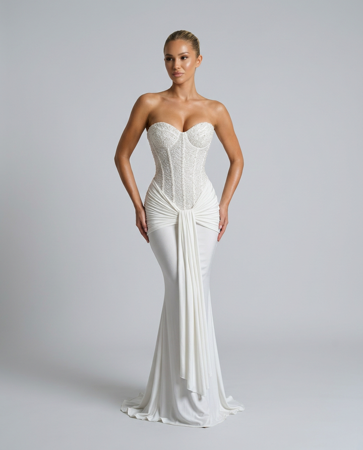 Witte strapless jurk met sleep, model poseert met handen langs de heupen en kijkt opzij 8