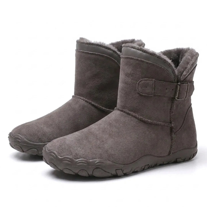 Paar grijsbruine suède enkellaarzen met bontvoering en gesp aan de zijkant, schuin van voren gefotografeerd 43