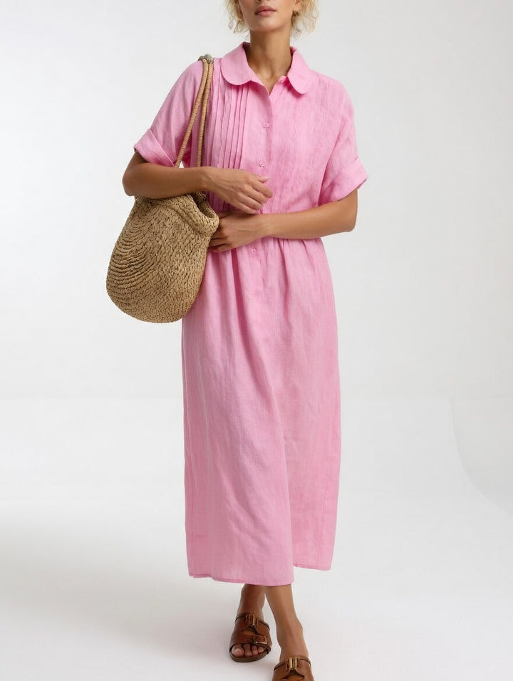Model draagt de roze uitvoering van voren, met een rieten tas over de schouder en de handen voor het lichaam. 4
