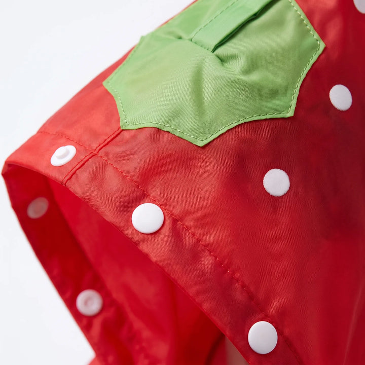 Close-up van rood jack met witte stippen, groen blaadje op de capuchon en witte drukknopen langs de rand. 6
