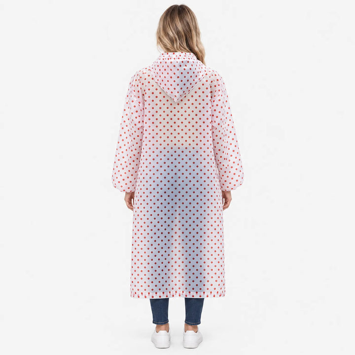 Achterkant van de doorzichtige regenjas met rode stippen, gedragen door een vrouw; de capuchon hangt op de rug, mouwen met elastische manchetten. 4
