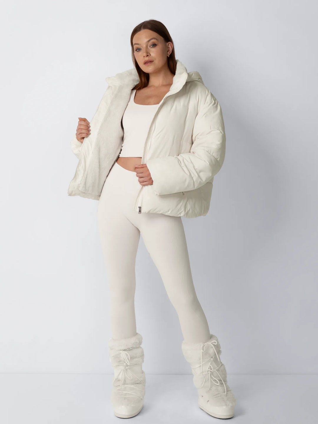 Model in crèmekleurige puffer met geopend voorpand, waardoor de fleece voering zichtbaar is, gecombineerd met moonboots 2