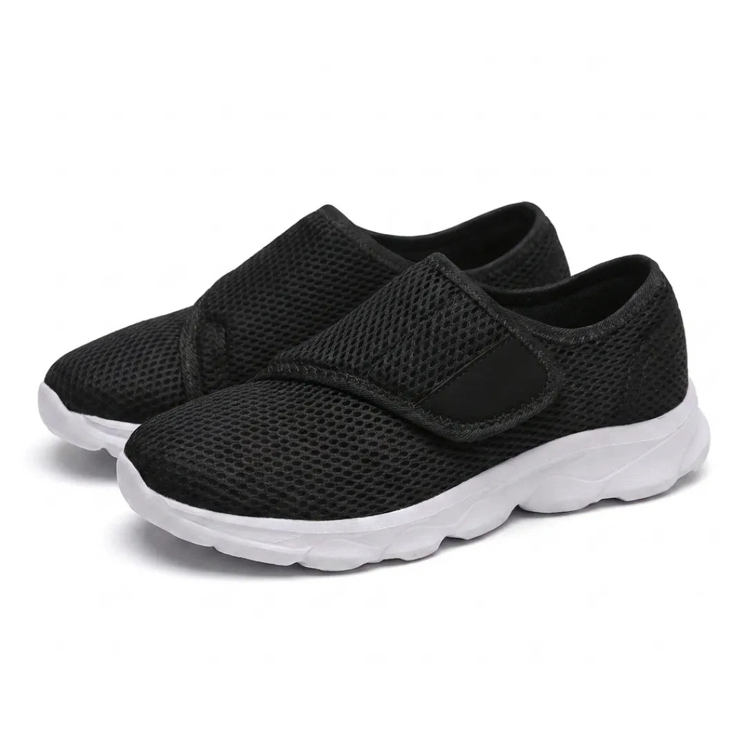 Paar zwarte mesh schoenen met witte zool en klittenbandsluiting, schuin van voren gefotografeerd. 25