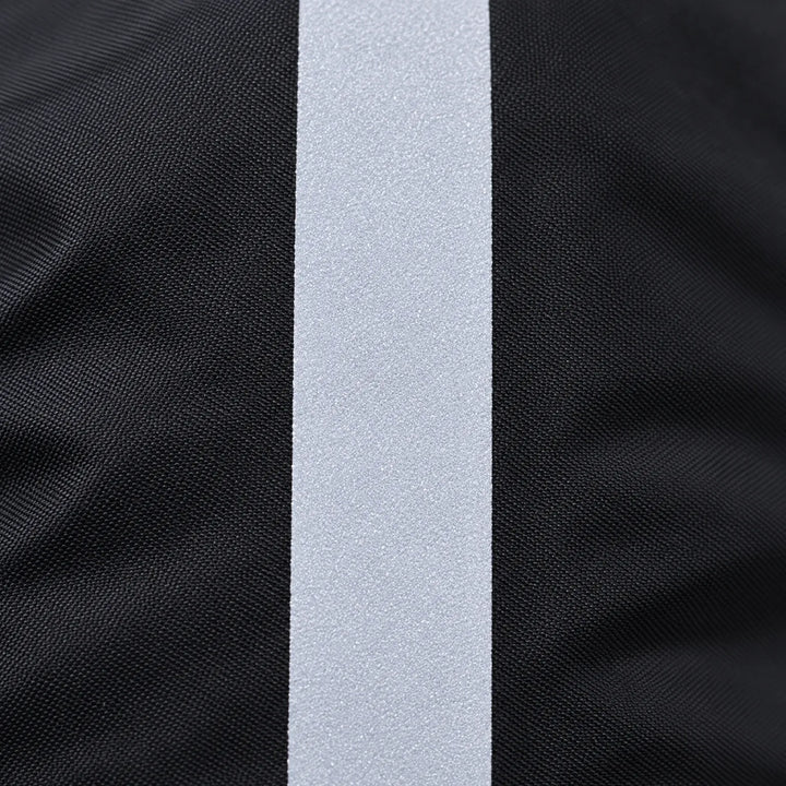Close-up van de lichtgrijze reflecterende strook op de fijn geweven zwarte stof van de regenhoes. 5