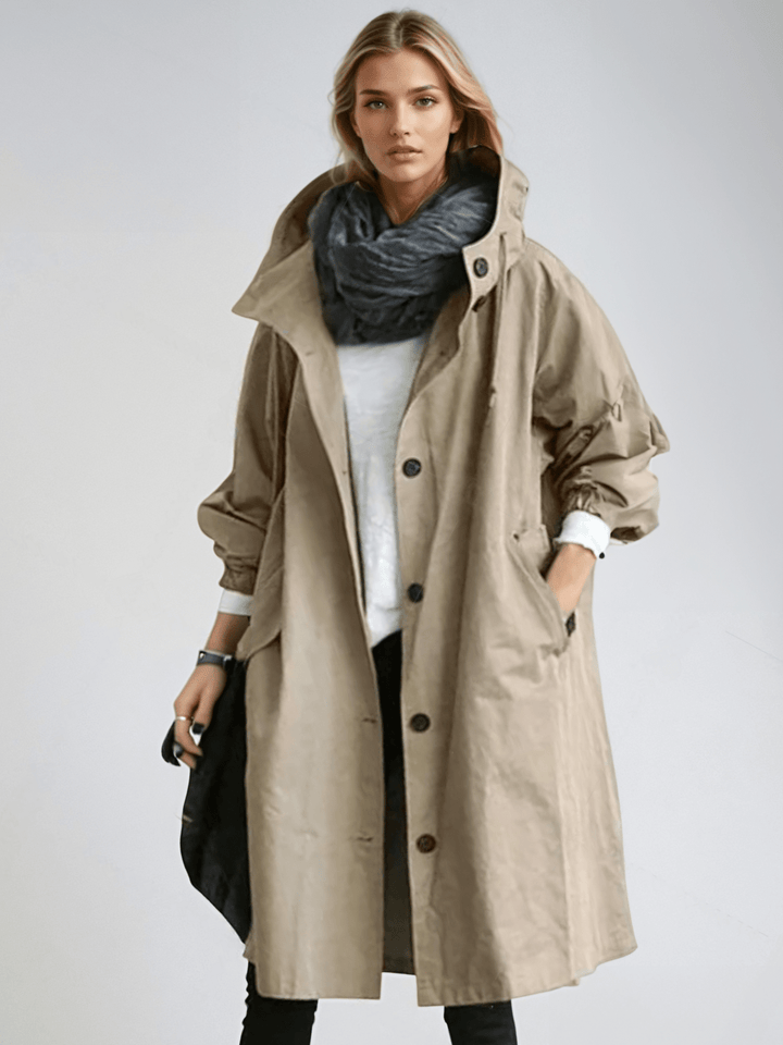 Model draagt de beige trenchcoat met opstaande kraag en knoopsluiting over een wit shirt, met donkere sjaal om de nek. 3