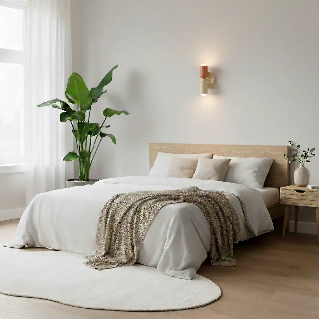 Wandlamp in terracotta en crème boven een tweepersoonsbed met neutrale beddengoed, een grote plant en een wit vloerkleed. 8