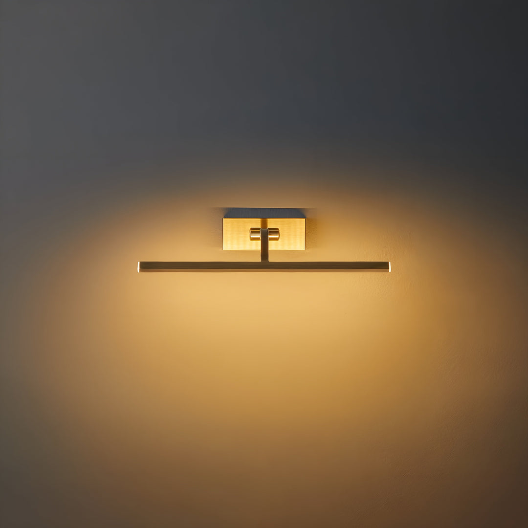 Frontaal aanstaande messing wandlamp met rechthoekige wandplaat en horizontale ledbalk, die warm licht op de muur werpt 1