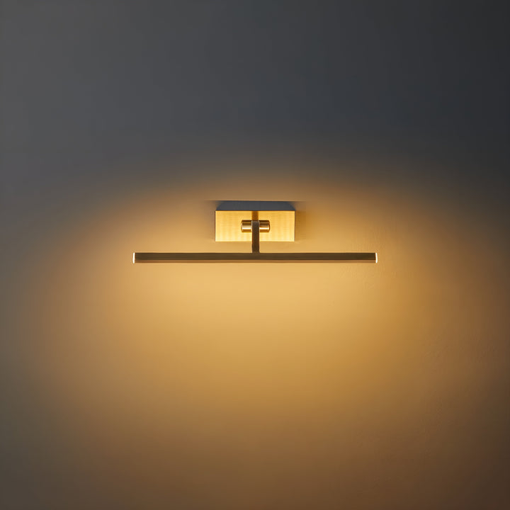 Frontaal aanstaande messing wandlamp met rechthoekige wandplaat en horizontale ledbalk, die warm licht op de muur werpt 1