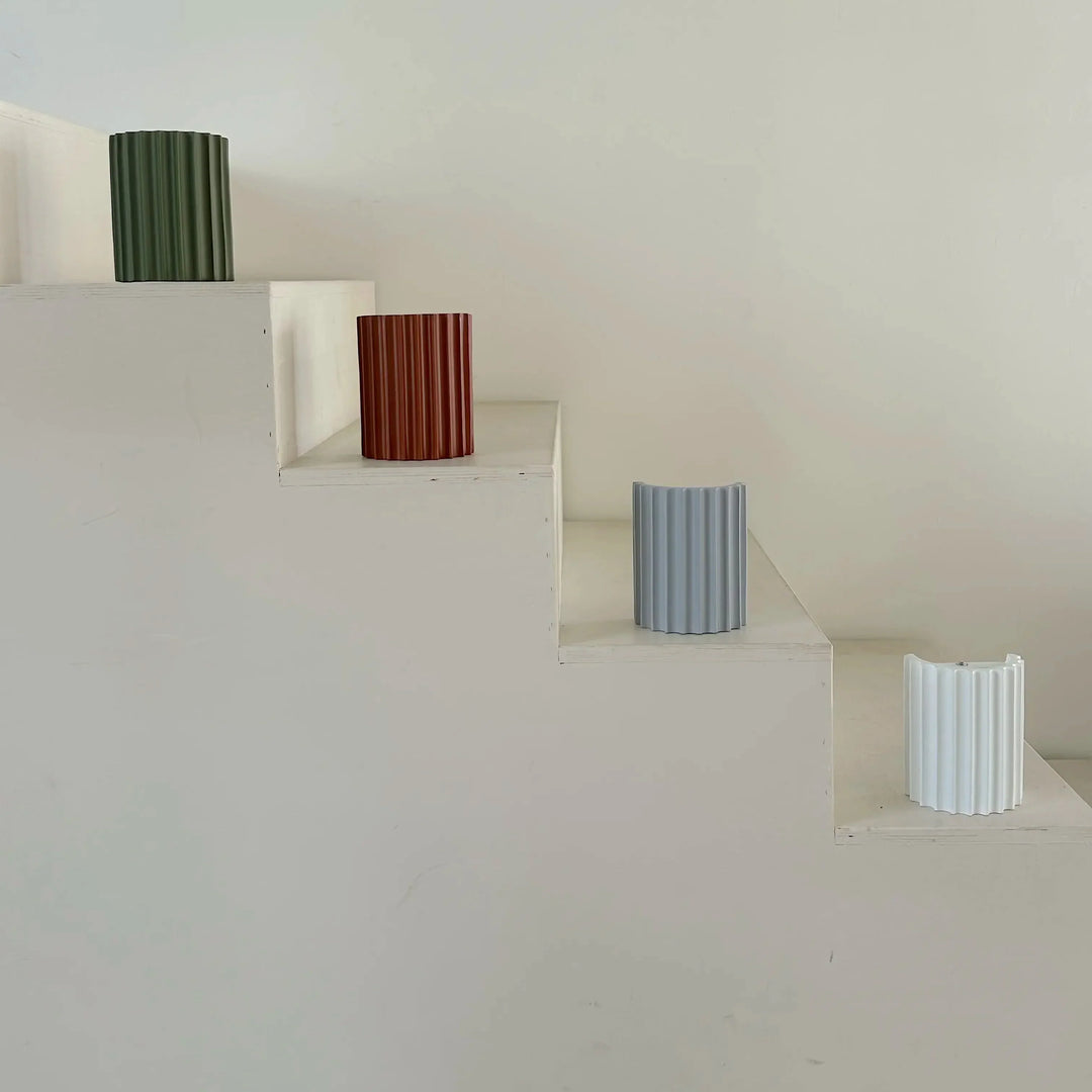 Vier geribbelde lampenkappen in groen, terracotta, lichtblauw en wit op een witte trap 10