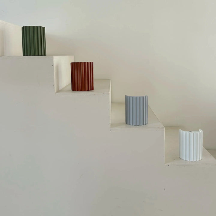 Vier geribbelde lampenkappen in groen, terracotta, lichtblauw en wit op een witte trap 10