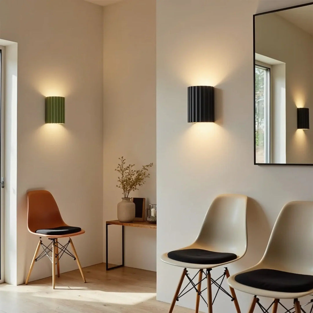 Groene en zwarte geribbelde wandlamp in een lichte woonkamer met stoelen, een spiegel en een bijzettafel 3