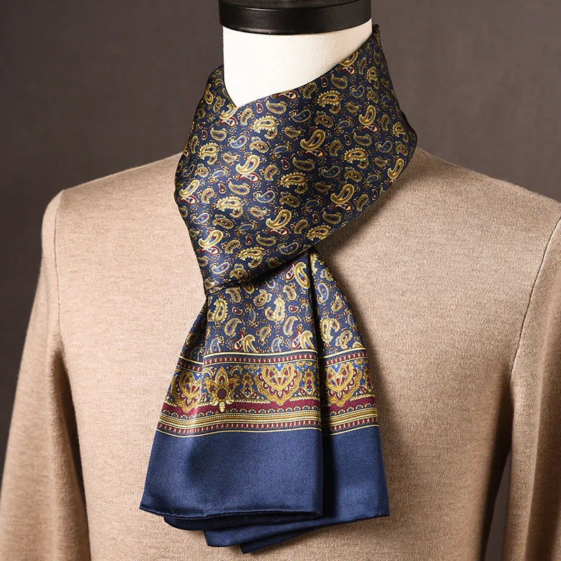 Marineblauwe zijden sjaal met gouden paisleymotief en brede sierrand, gedragen op een paspop met beige trui. 12