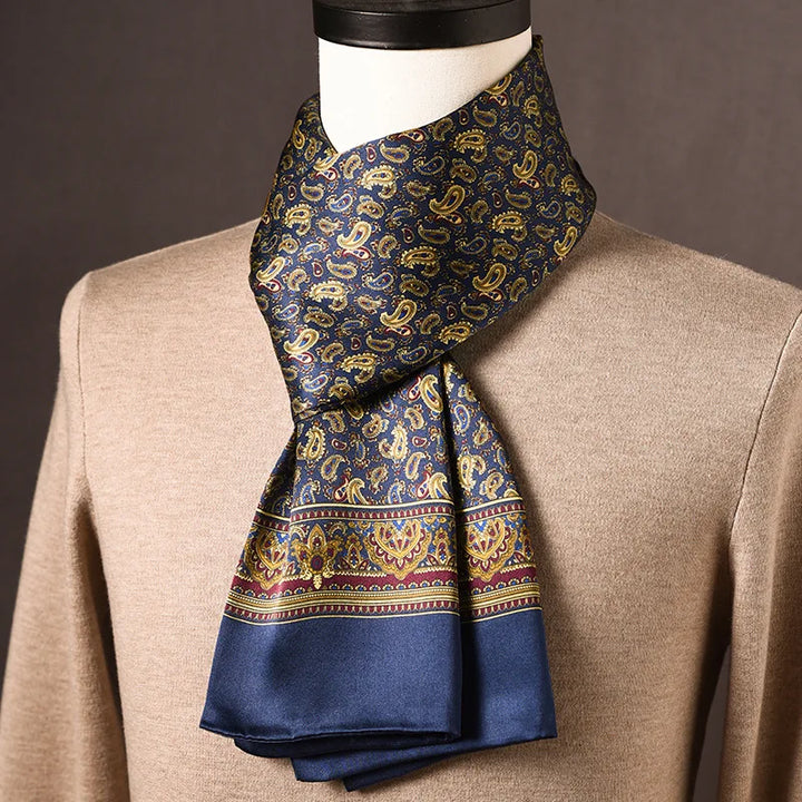 Marineblauwe zijden sjaal met gouden paisleymotief en brede sierrand, gedragen op een paspop met beige trui. 12