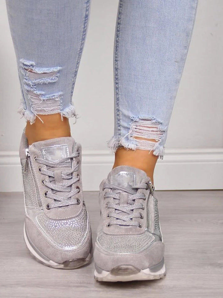 Grijze damessneakers met glittersteentjes en veters, van voren gezien aan de voeten van een model 6