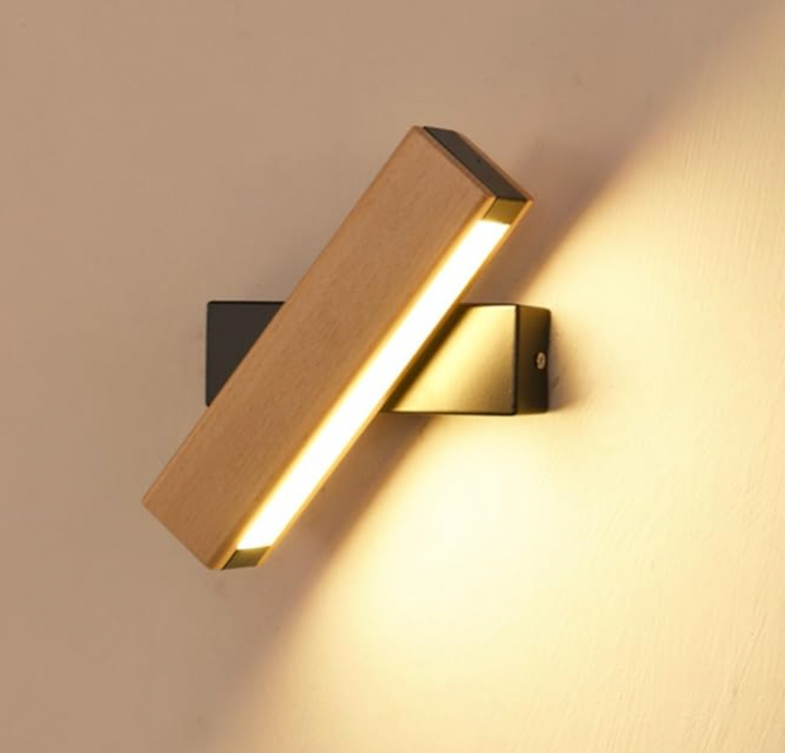 Close-up van de houten ledwandlamp met zwarte bevestiging, schuin gedraaid, waarbij de lichtstrip warm licht op de muur werpt. 7