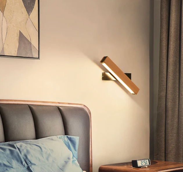Draaibare houten wandlamp boven een bed met grijs hoofdeinde en blauw kussen, naast een gordijn en een digitale klok. 8