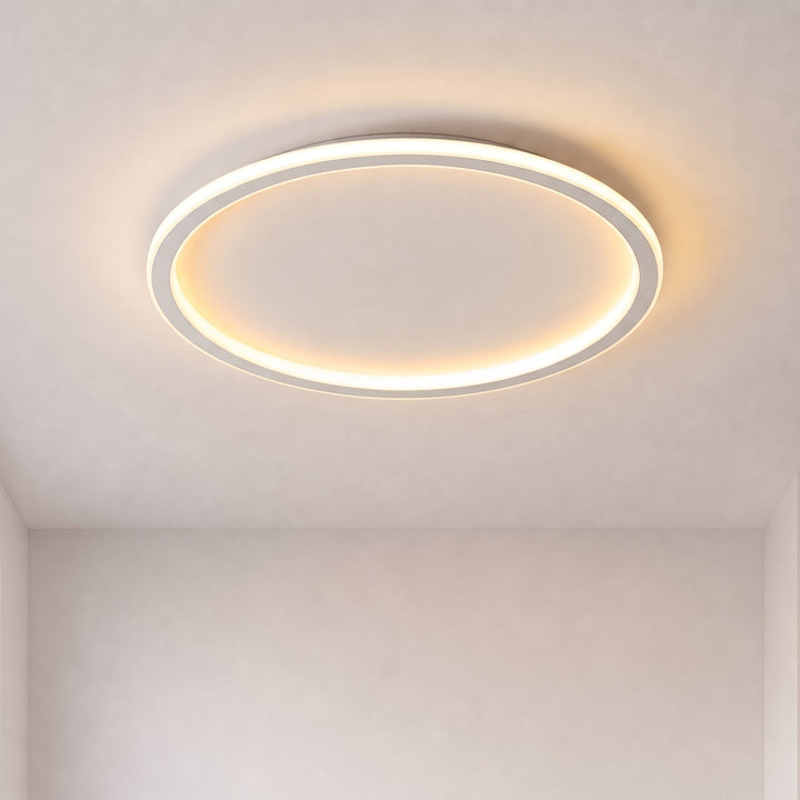 Ronde witte led-plafondlamp met lichtgevende ring brandt warm tegen een kaal plafond in een lege kamer. 1