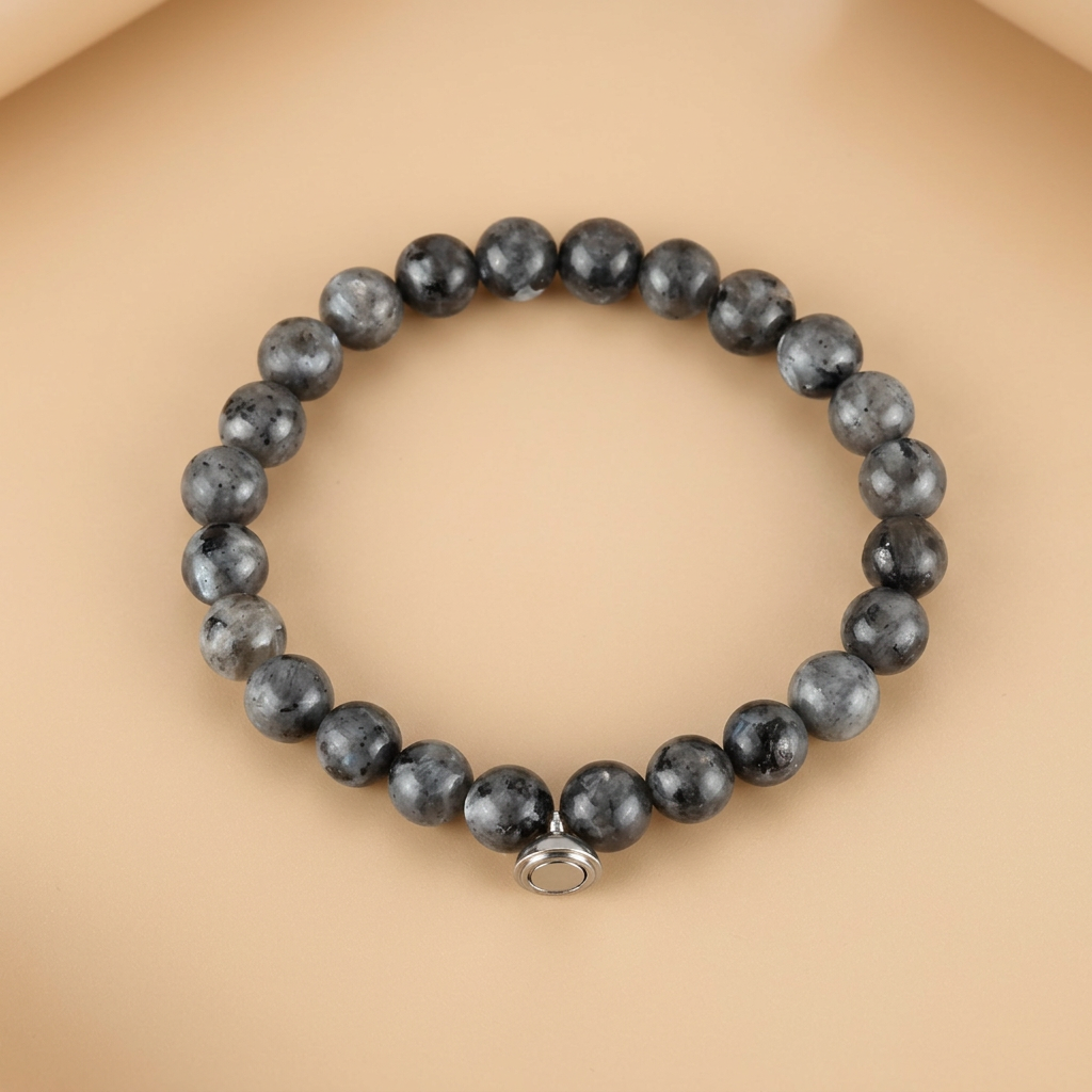 Armband van grijze, zwart gevlekte kralen met zilverkleurige magneetsluiting op een zachte perzikkleurige ondergrond 4