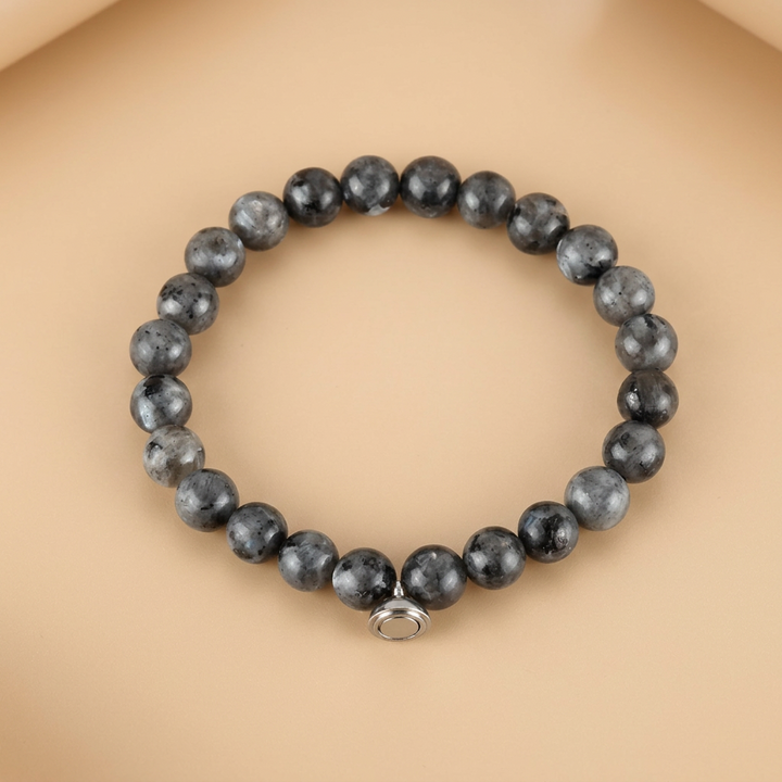 Armband van grijze, zwart gevlekte kralen met zilverkleurige magneetsluiting op een zachte perzikkleurige ondergrond 4