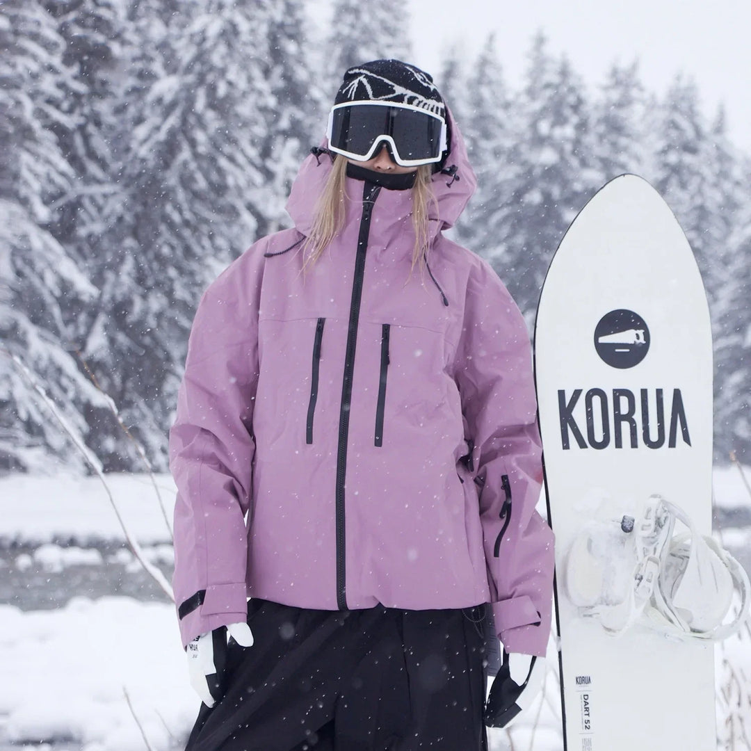 Model in roze jas met zwarte ritsen houdt een snowboard vast, tussen besneeuwde dennenbomen. 3