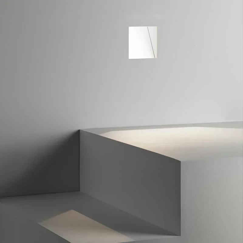 Vierkante witte inbouwlamp hoog in de wand, met licht dat op trapvormige treden valt 10