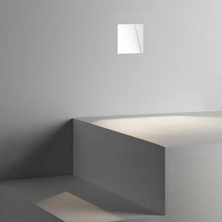 Vierkante witte inbouwlamp hoog in de wand, met licht dat op trapvormige treden valt 10
