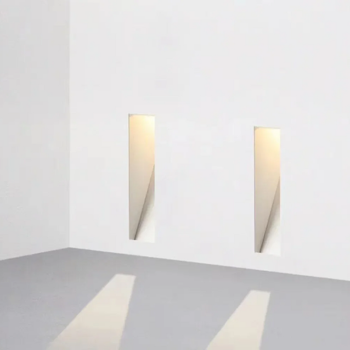 Twee smalle, verticale ingebouwde wandlampen in een witte hoek, met lichtkegels op de vloer 5